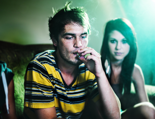 man smoking a joint in front of a woman