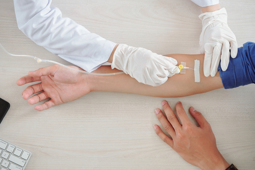 person receiving an iv from a doctor in their arm