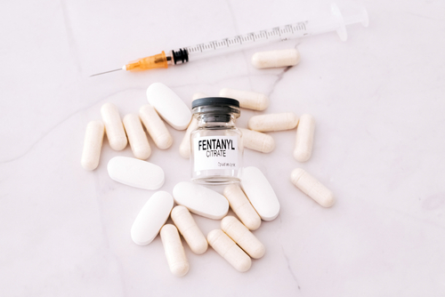 fentanyl pills, bottle, and syringe on white background