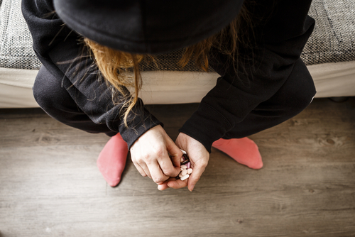 person sitting on couch with pills in hand about to take them