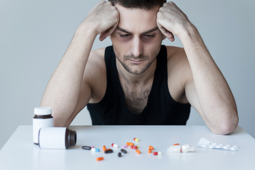 man looking down at pills scattered on the counter