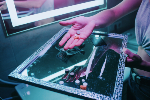 person holding pills and powder on a tray while at a party